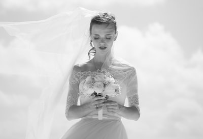 新娘手持花束的灰度照片